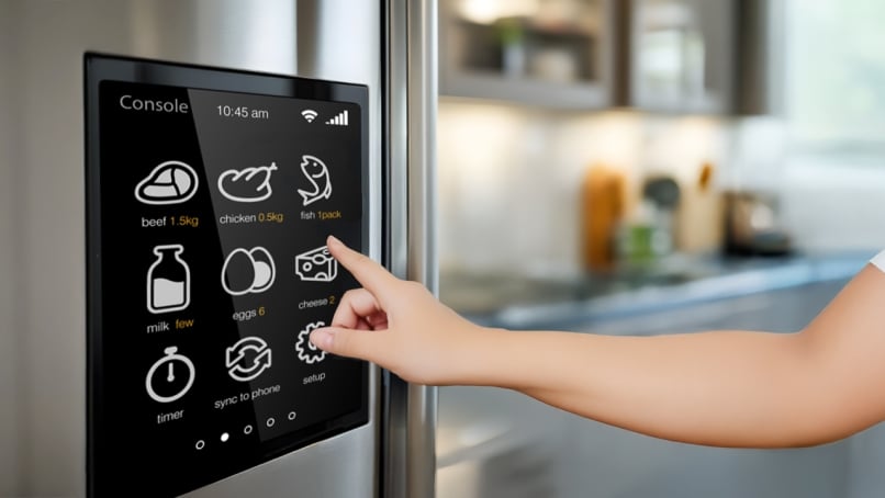 Finger touching refrigerator door's console touchscreen with kitchen background
