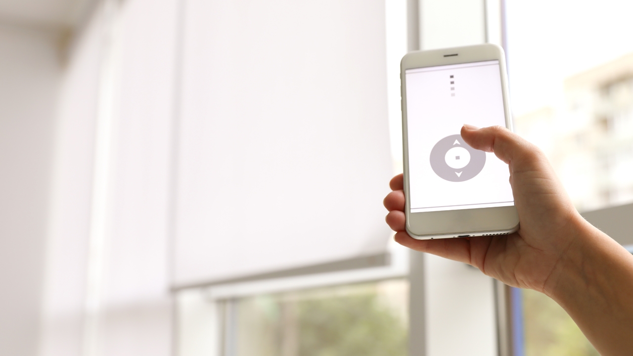 Hand holding mobile with app to controlling window shading.