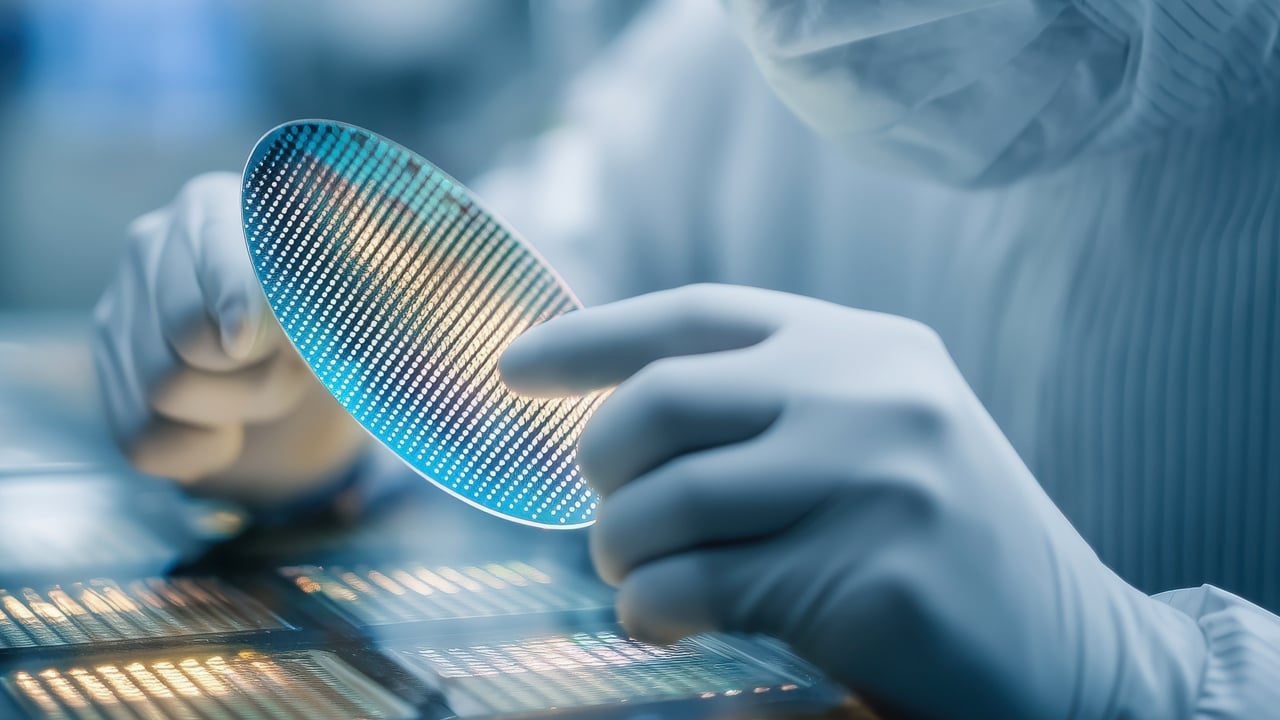 Technician closely examining semiconductor wafer in a facility.