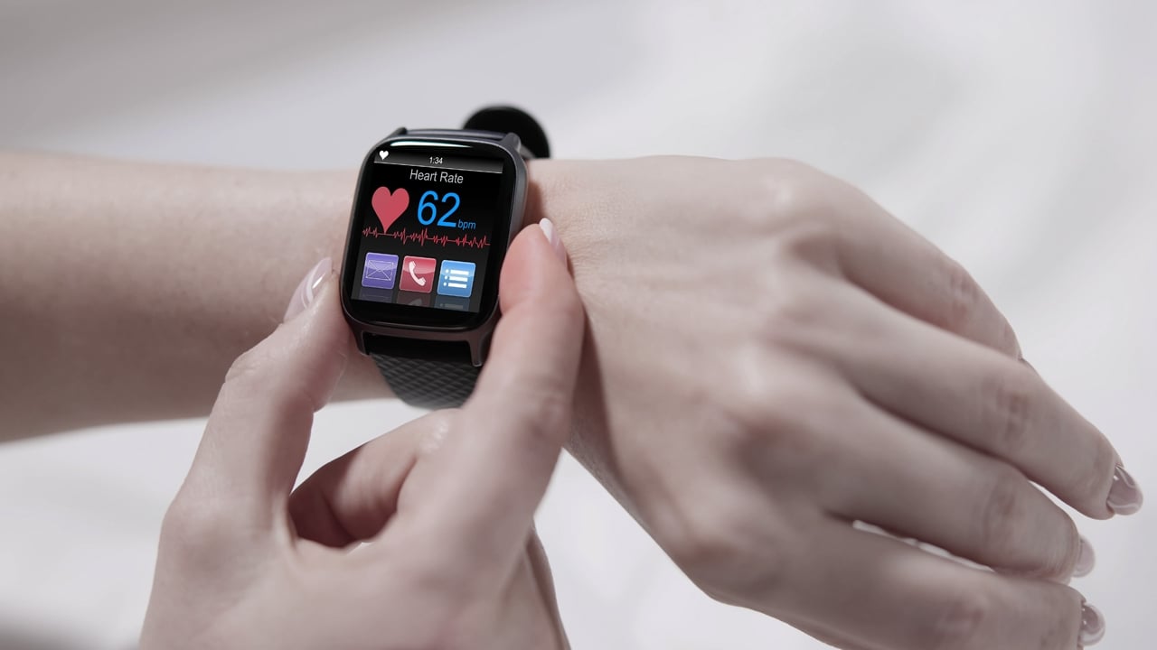 Smart watch on wrist showing heartrate monitor and other apps on interface.