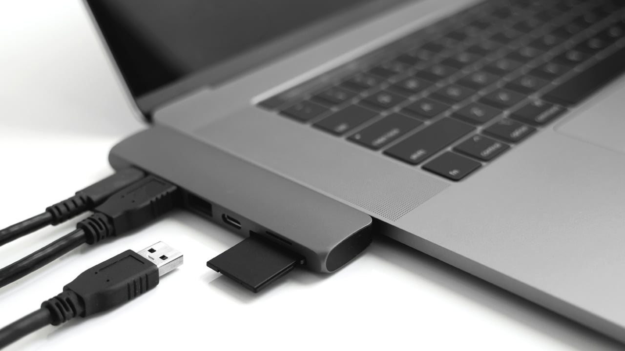 Laptop with USB Type-C adapter with plugged USB cables and SD card.